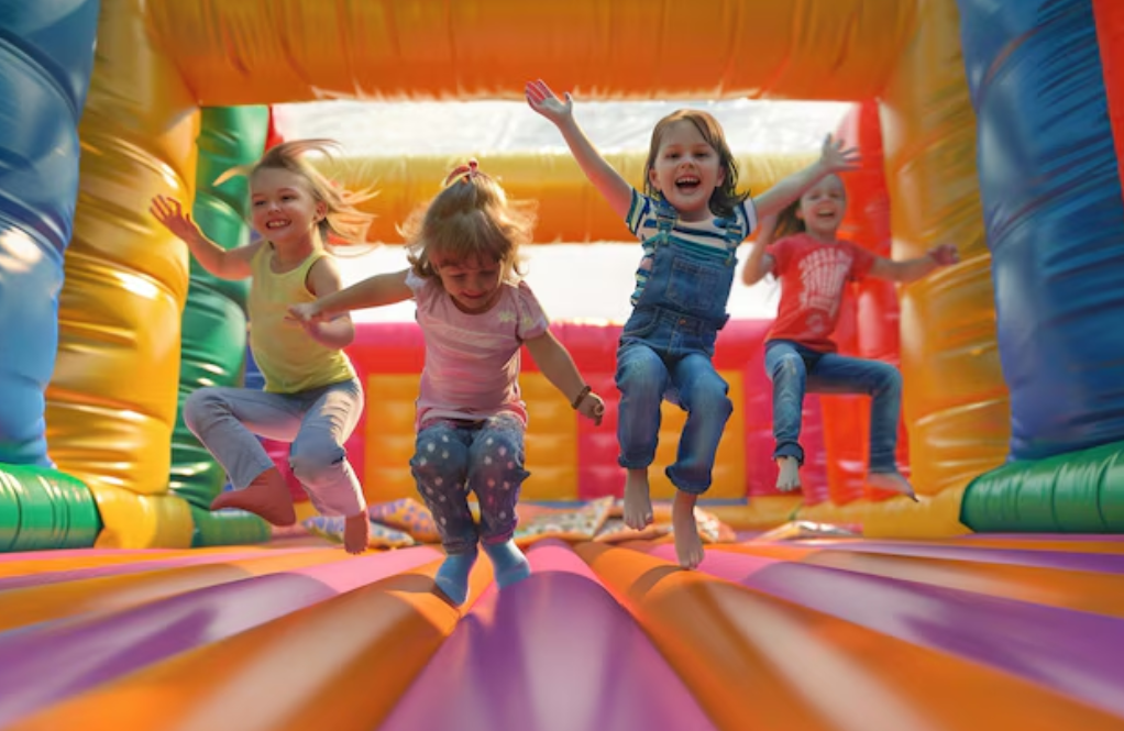 Bounce House Rentals in Wilmington DE Group of children joyfully jumping inside a bright, inflatable bounce house at an outdoor event.